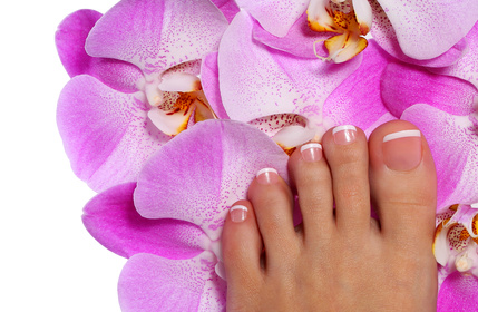 Pedicure with pink orchid flower. Beautiful female foot